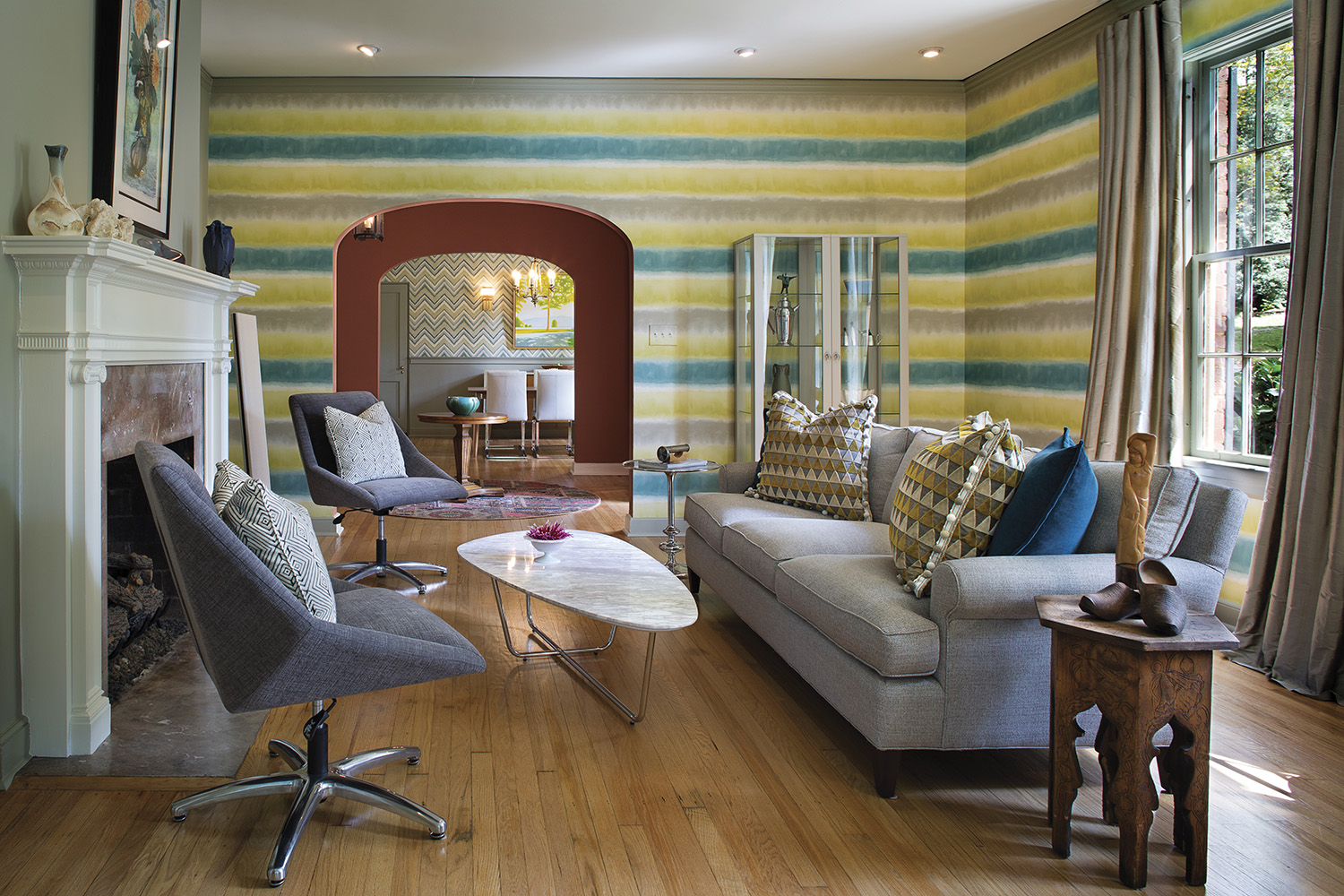 Striped wallpaper applied horizontally makes a bold statement in the living/listening room. The sofa is from Four Corners Home, the chairs and coffee table are from Mobilia; custom draperies (Libas Bhopal Silk Dupioni) and pillows (Harlequin Tessalatte) are by KWL Design & Décor. Photo by David Dietrich