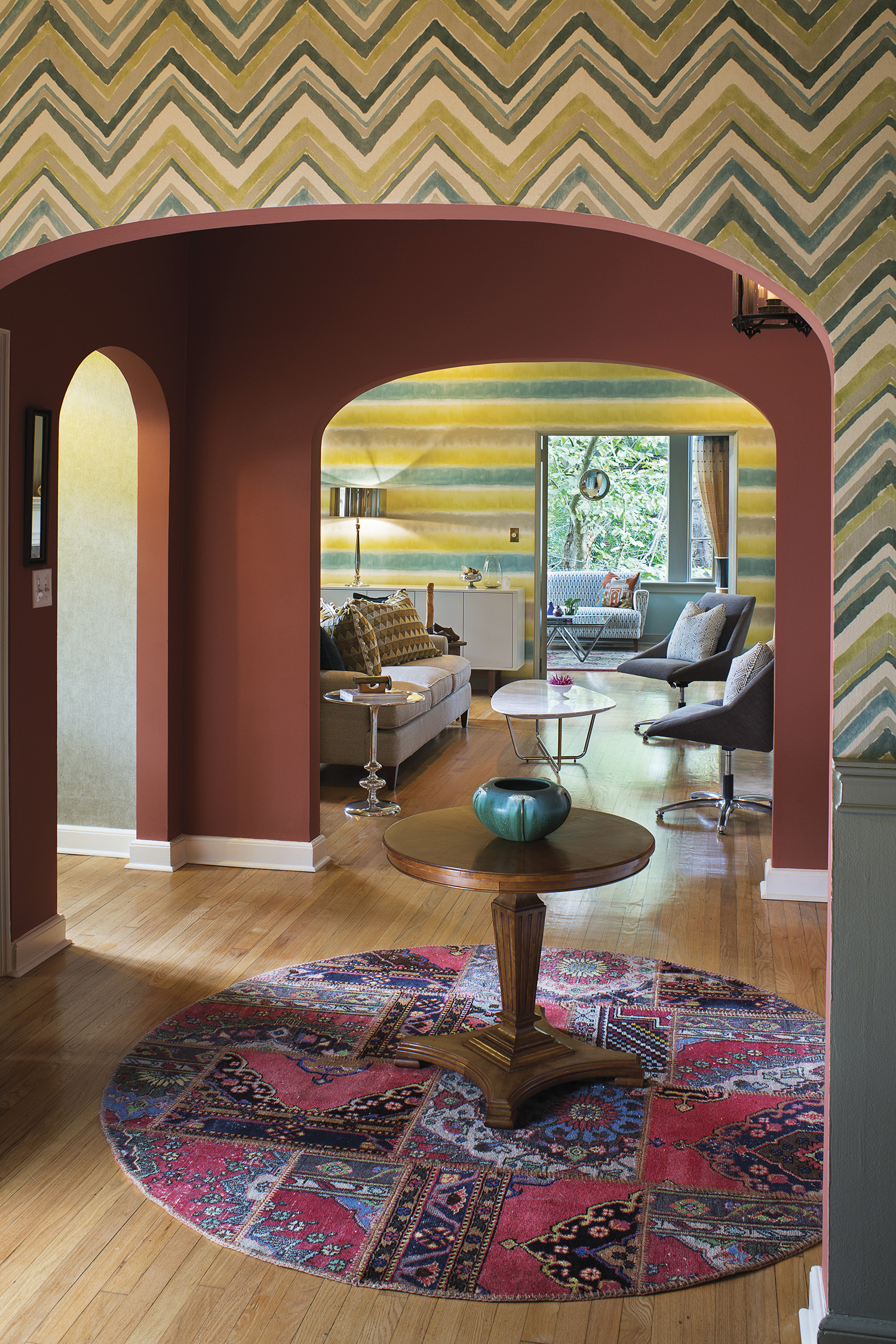 The warm color in the foyer matches the hue of the exterior brick and becomes a roomy central circulation space against the cool colors of the living and dining areas, decorated with wallpaper from Sanderson and Harlequin brands. Rug from Togar. Photo by David Dietrich