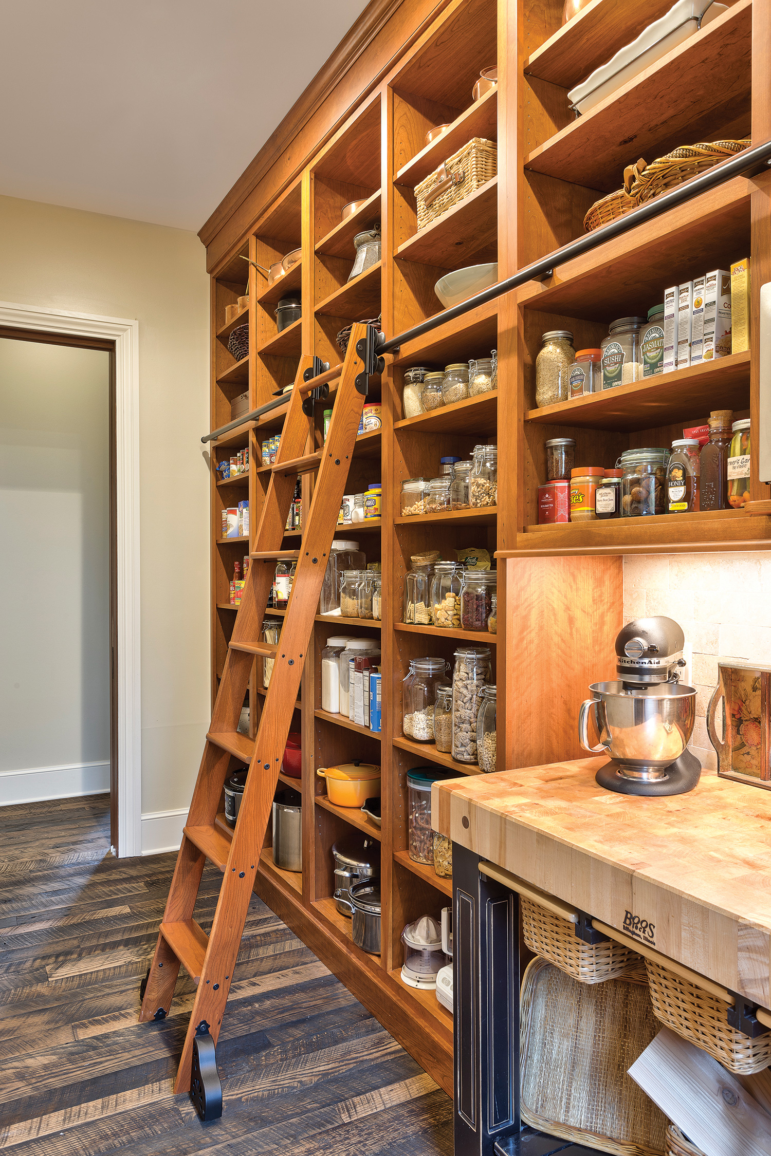 This roomy pantry, adjacent to a farmhouse-inspired kitchen, has open shelves of stained alder with a library ladder. Photo by Kevin Meechan.