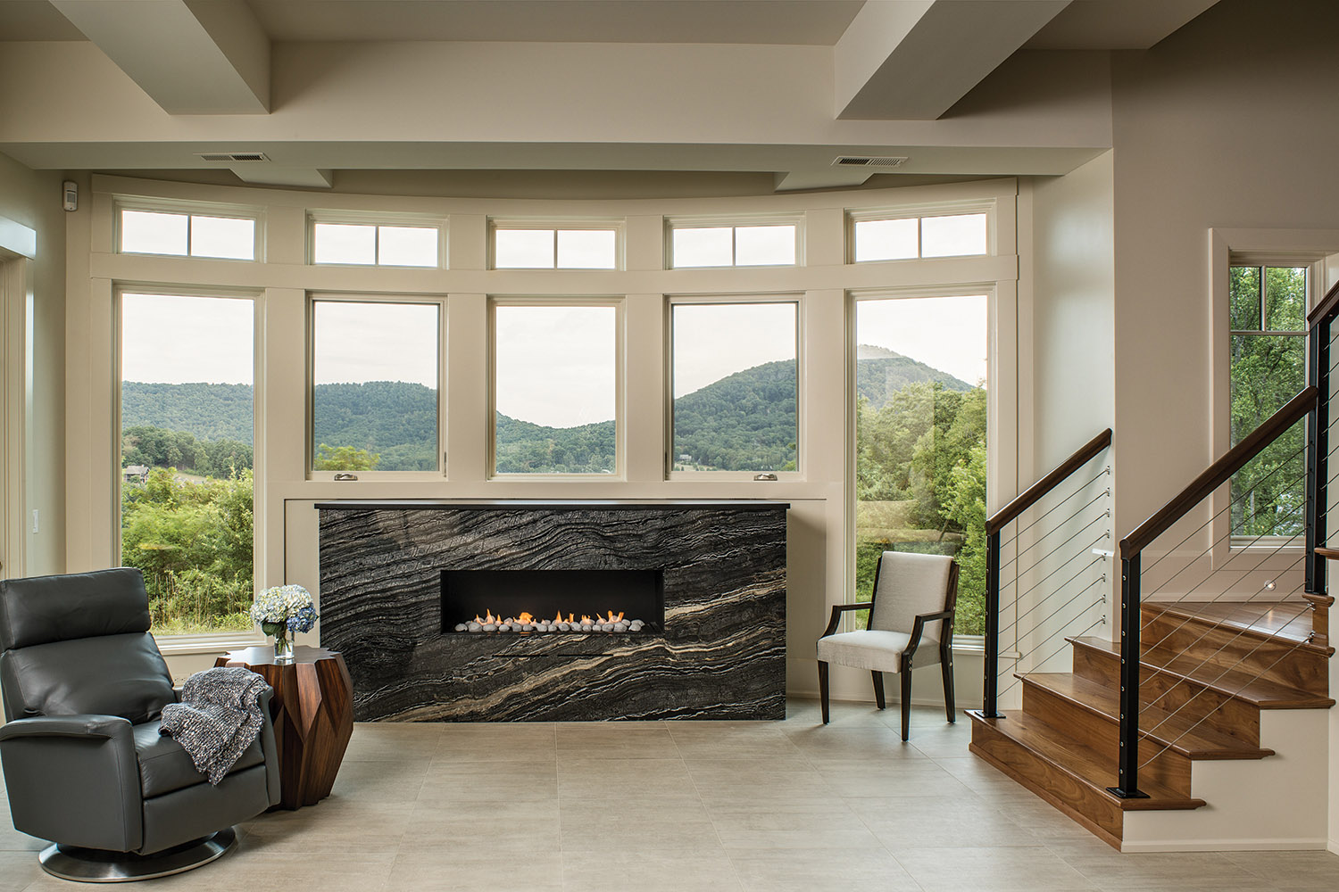 A granite fireplace and shelf — fabricated & installed by Mountain Marble — offer guests on the terrace level an additional level of comfort. The gas unit is set into a curved wall of windows. Photo by David Dietrich